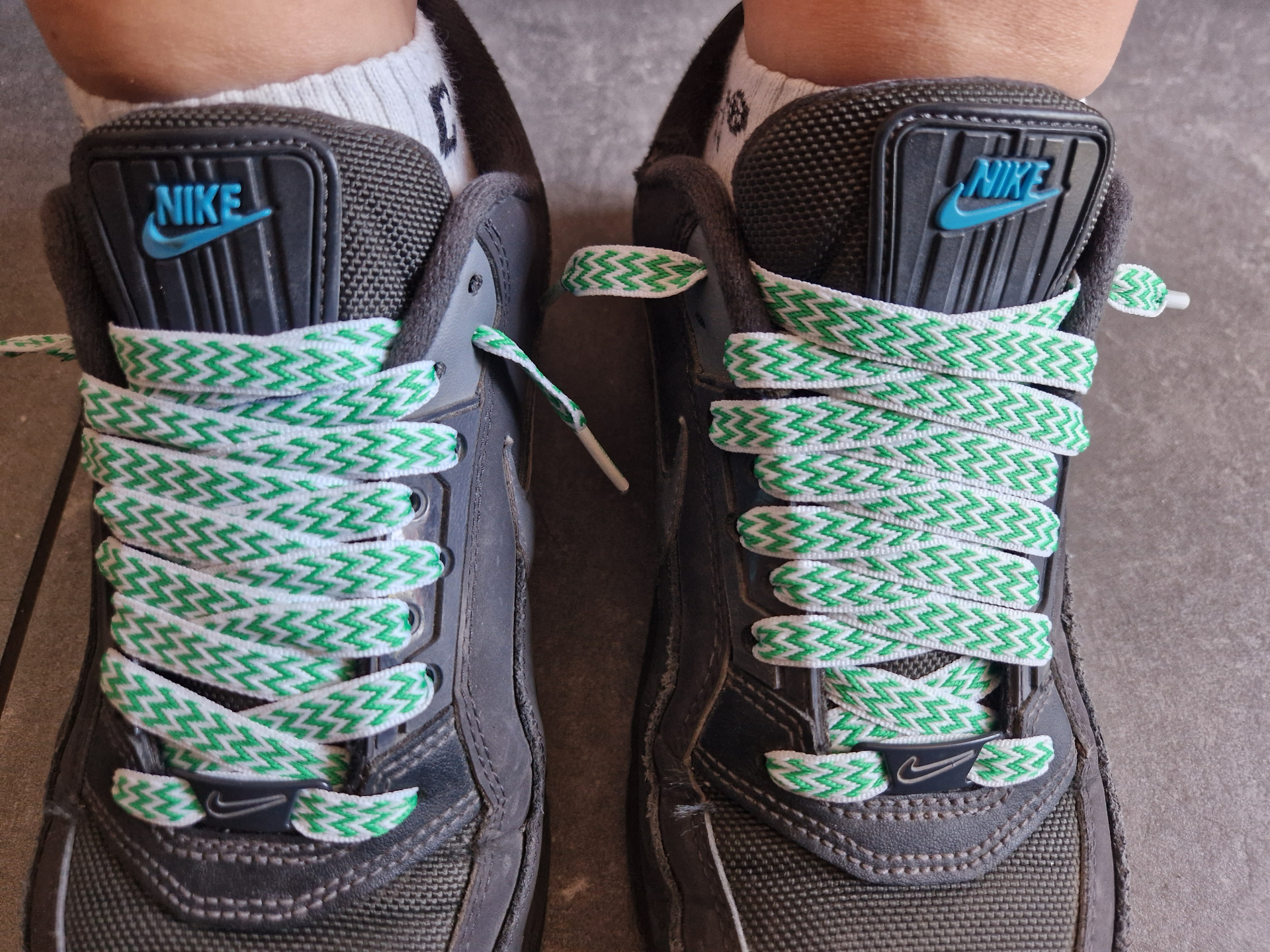Groen-witte veters in een paar donkergrijze schoenen, aan de voet